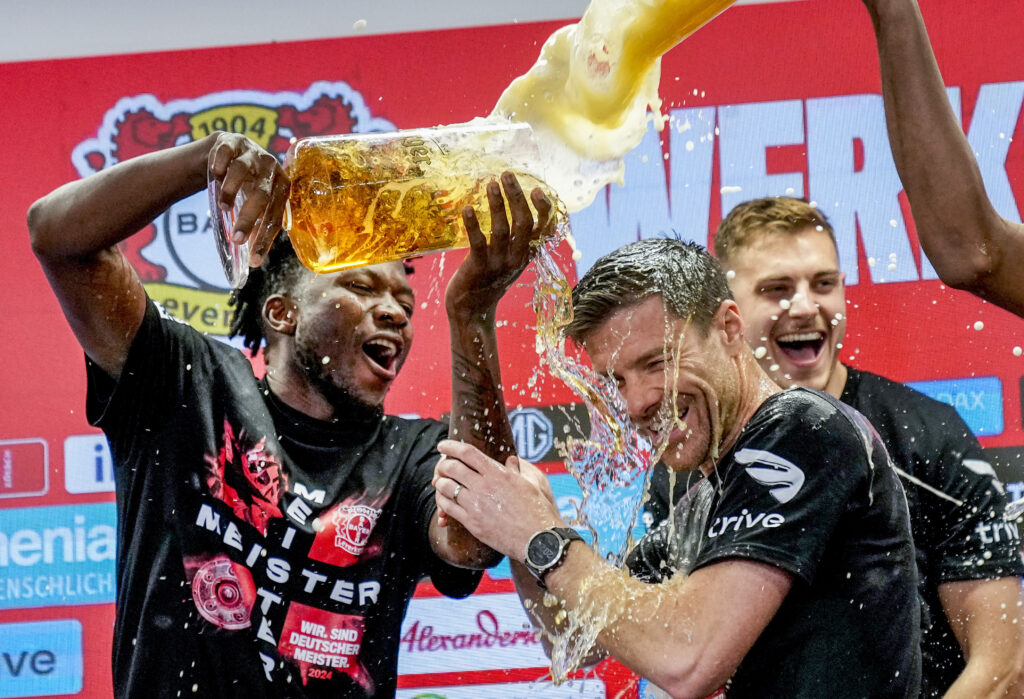 Leverkusen's head coach Xabi Alonso , centre, is sprayed with beer after Bayer Leverkusen won the German Bundesliga title beating Werder Bremen in Leverkusen, Germany, Sunday, April 14, 2024. (AP Photo/Martin Meissner)