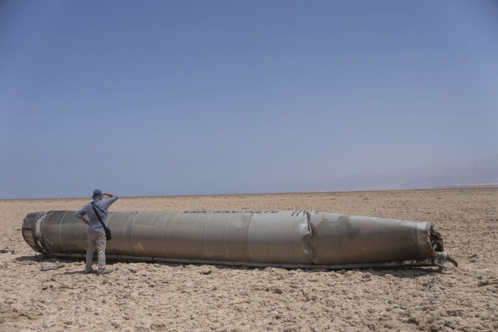 A photojournalist looks at part of the intercepted ballistic missile that fell near the Dead Sea in Israel, Sunday, April 21, 2024. The suspected Israeli killing of Iranian generals at an Iranian diplomatic compound in Syria on April 1 prompted Iran's retaliatory barrage last weekend of more than 300 missiles and drones that the U.S., Israel and regional and international partners helped bat down without significant damage in Israel. And then came Friday’s apparent Israeli strike. (AP Photo/ Ohad Zwigenberg)