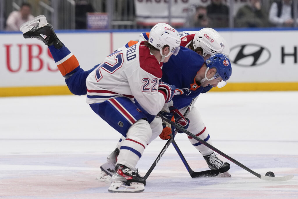 New York Islanders' Adam Pelech, center, is squeezed by Montreal Canadiens' Cole Caufield, left, and Jake Evans during the second period of an NHL hockey game Thursday, April 11, 2024, in Elmont, N.Y. (AP Photo/Seth Wenig)