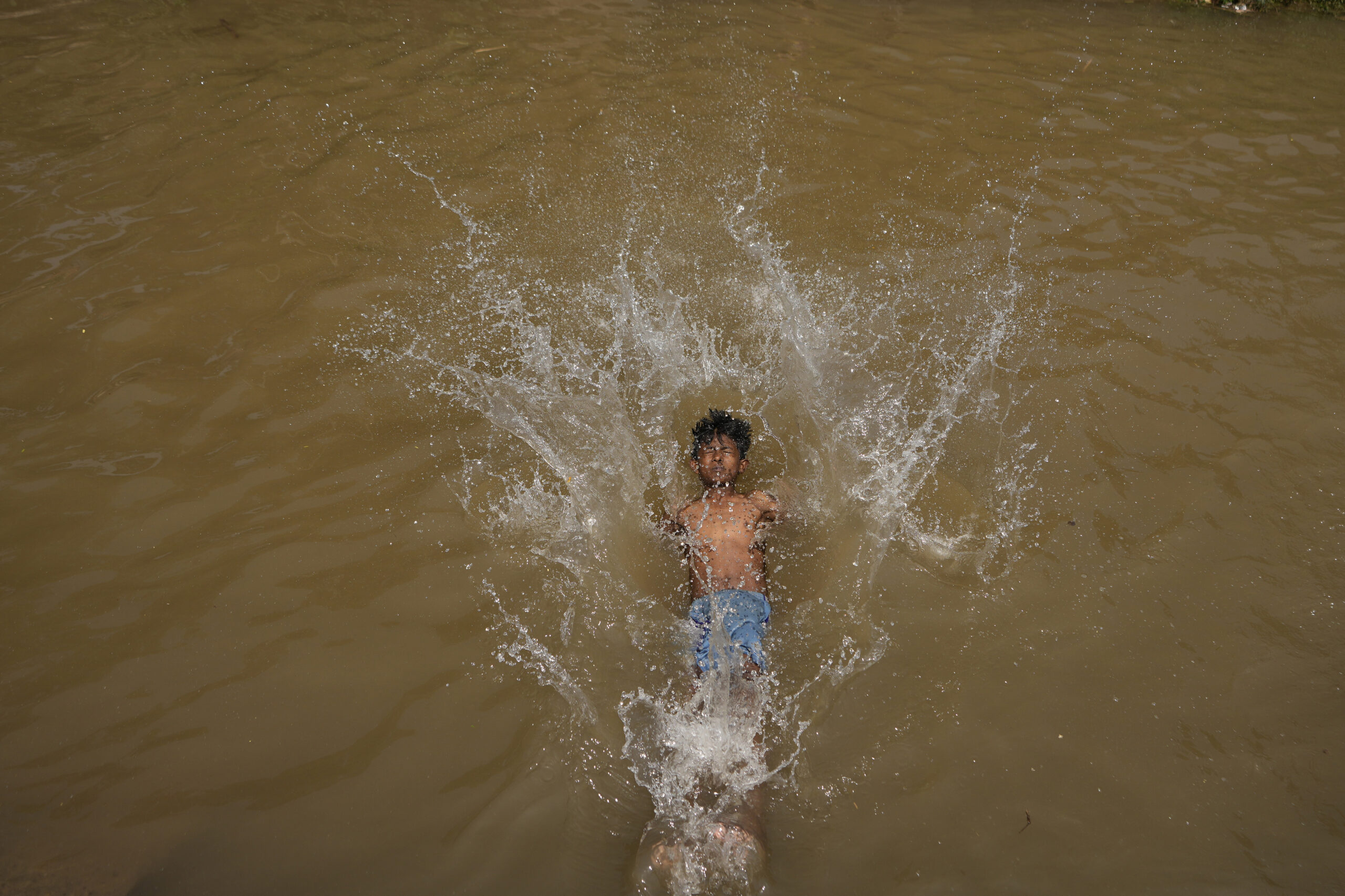 A boy bathes in a canal to cool himself on a hot summer afternoon in Jammu, India, Wednesday, May 8, 2024. (AP Photo/Channi Anand)