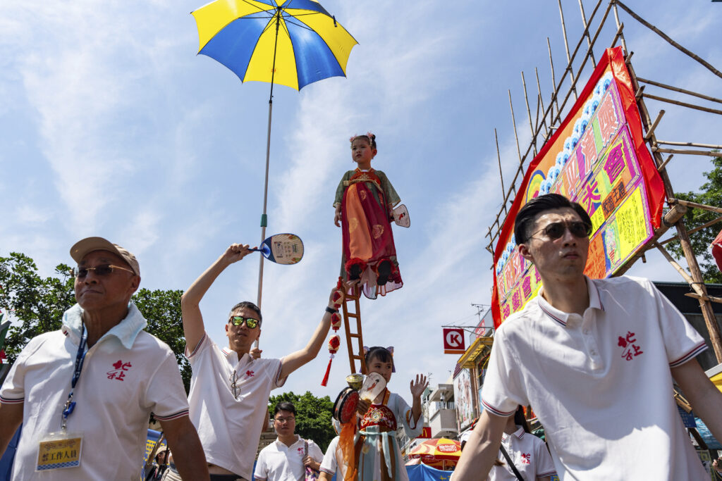 A child is hoisted up as participants take part in the Piu Sik Parade at the Bun Festival in Cheung Chau Island in Hong Kong, Wednesday, May 15, 2024. (AP Photo/Chan Long Hei)