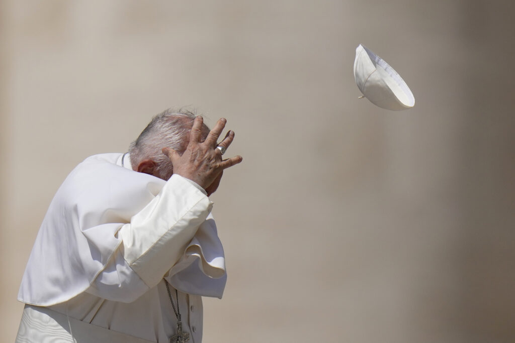 Pope Francis tries to catch his cap as wind blew it away while leaving after his weekly general audience in St. Peter's Square at The Vatican, Wednesday, May 15, 2024. (AP Photo/Alessandra Tarantino)