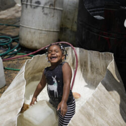 A girl plays in a water container in the Los Guandules neighborhood of Santo Domingo, Dominican Republic, Monday, May 20, 2024. (AP Photo/Matias Delacroix)