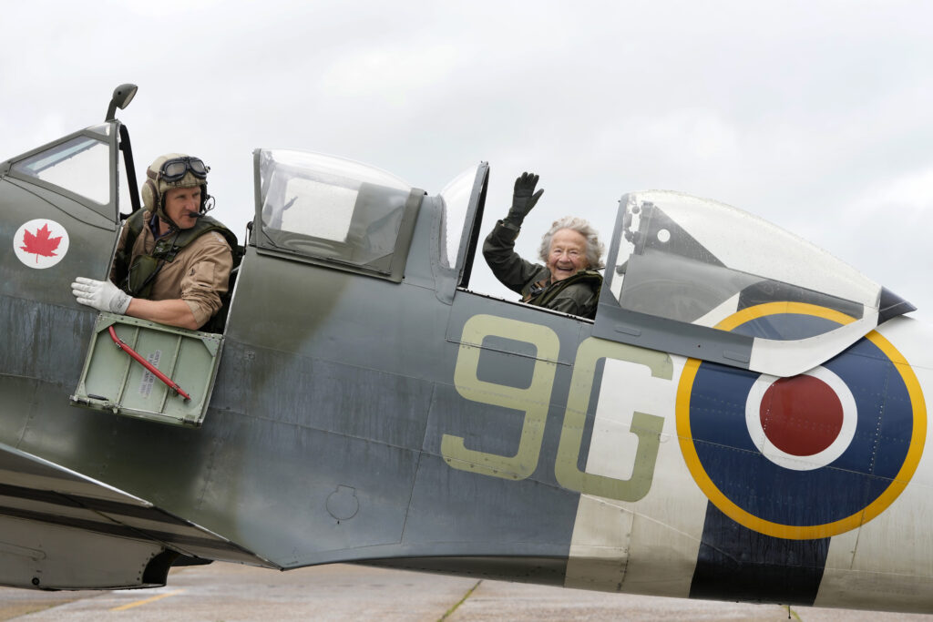 Dorothea Barron, aged 99, who was a serving Wren at the time of D-Day sits in a Spitfire with pilot Jeremy Britcher at Biggin Hill Airport in Kent, England, Tuesday, May 28, 2024. The Taxi Charity for Military Veterans took WWII veterans, including Normandy veterans, to an event at the Biggin Hill Heritage Hangar just ahead of their trip to Normandy for the D Day 80th Anniversary. (AP Photo/Kirsty Wigglesworth)