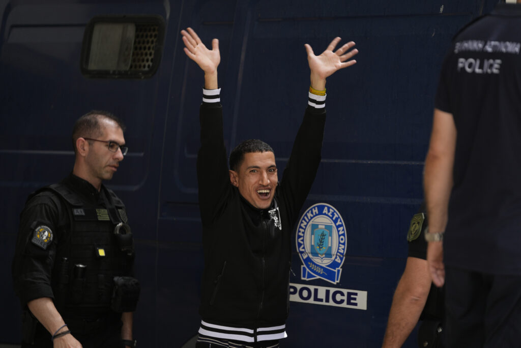 One of nine Egyptians, who was on trial for migrant smuggling, waves to the media persons as he leaves the court in Kalamata, southwestern Greece, on Tuesday, May 21, 2024. A Greek judge dismissed charges against nine Egyptian men accused of causing a shipwreck that killed hundreds of migrants last year and sent shockwaves through the European Union's border protection and asylum operations, after a prosecutor told the court Greece lacked jurisdiction. (AP Photo/Thanassis Stavrakis)