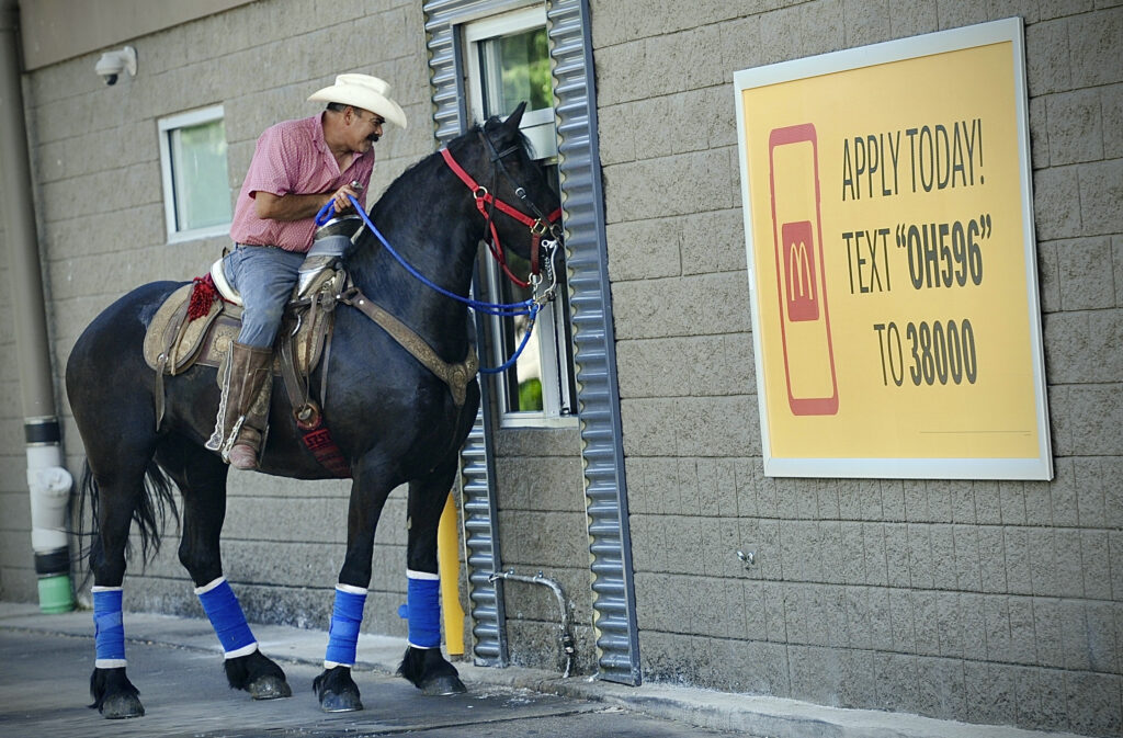 Ramón Martinez Prieto, on his horse Nikki, goes through the drive-through at the McDonald's in the Clark County village of Enon, Ohio, Saturday, May 25, 2024, to pick up lunch. (Marshall Gorby/Dayton Daily News via AP)