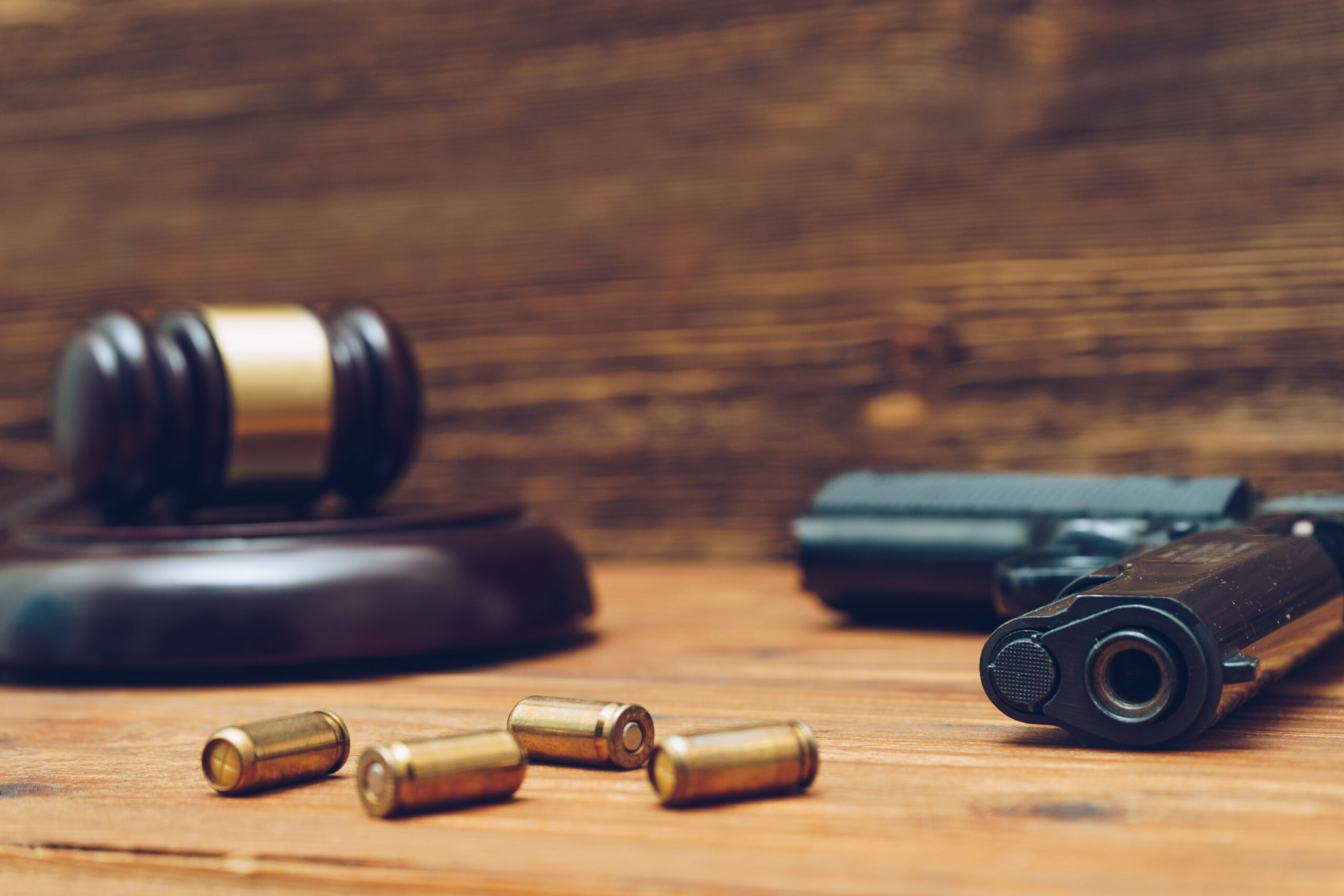 Judge gavel, handgun and bullets on wooden background.