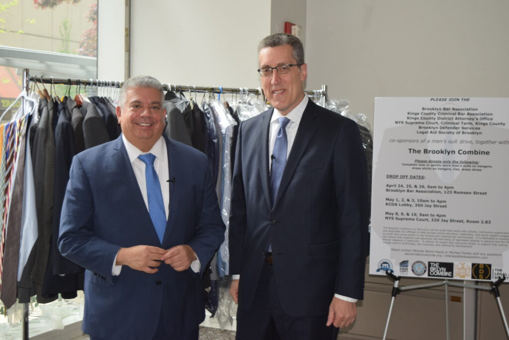District Attorney Eric Gonzalez and attorney Michael Farkas proudly display a collection of approximately 100 suits gathered during their suit drive at the DA's Office on Jay Street, aimed at empowering Brooklyn's youth. Brooklyn Eagle photos by Robert Abruzzese