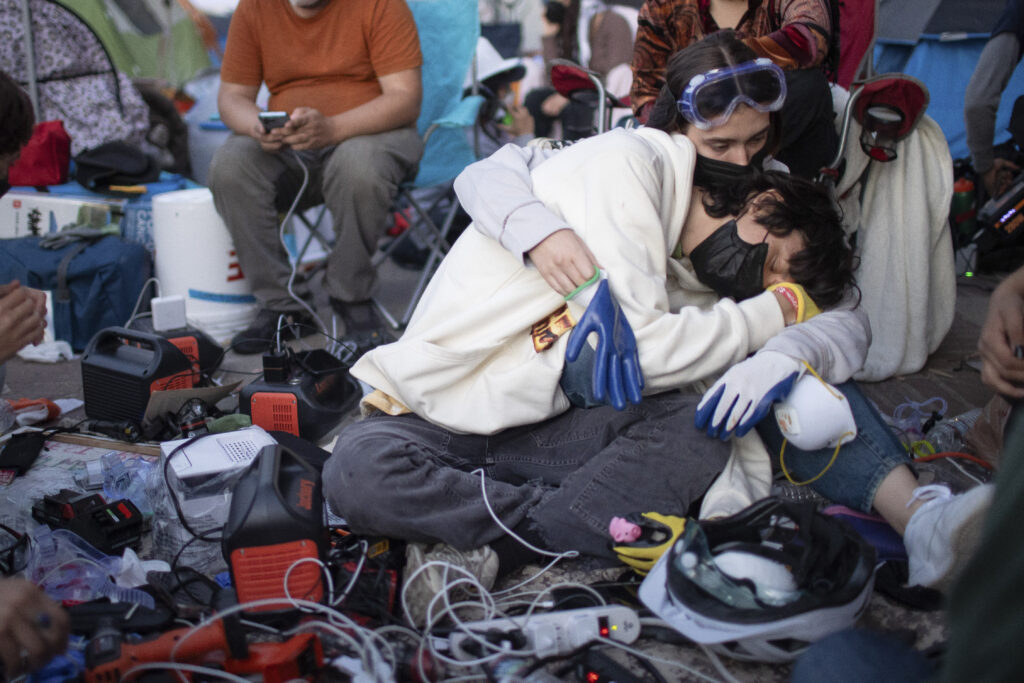Pro-Palestinian demonstrators embrace while charging devices at an encampment on the UCLA campus Wednesday, May 1, 2024, in Los Angeles. (AP Photo/Ethan Swope)