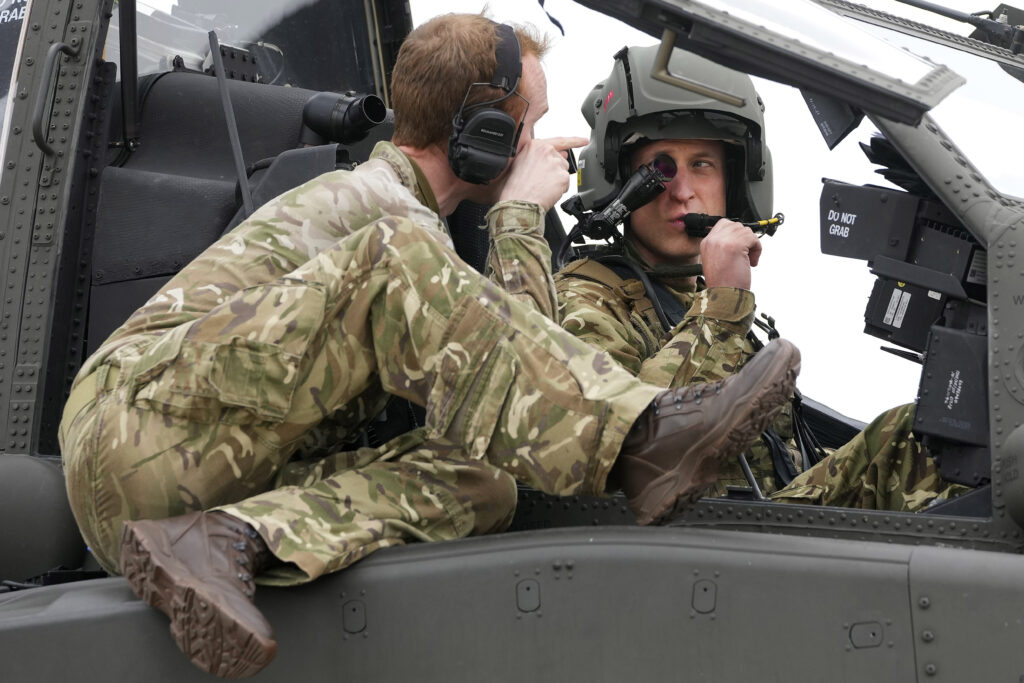 Britain's Prince William gets advice as he sits in an Apache helicopter at the Army Aviation Centre in Middle Wallop, England, Monday, May 13, 2024. King Charles III officially handed over the role of Colonel-in-Chief of the Army Air Corps to Prince William, The Prince of Wales. (AP Photo/Kin Cheung, Pool)