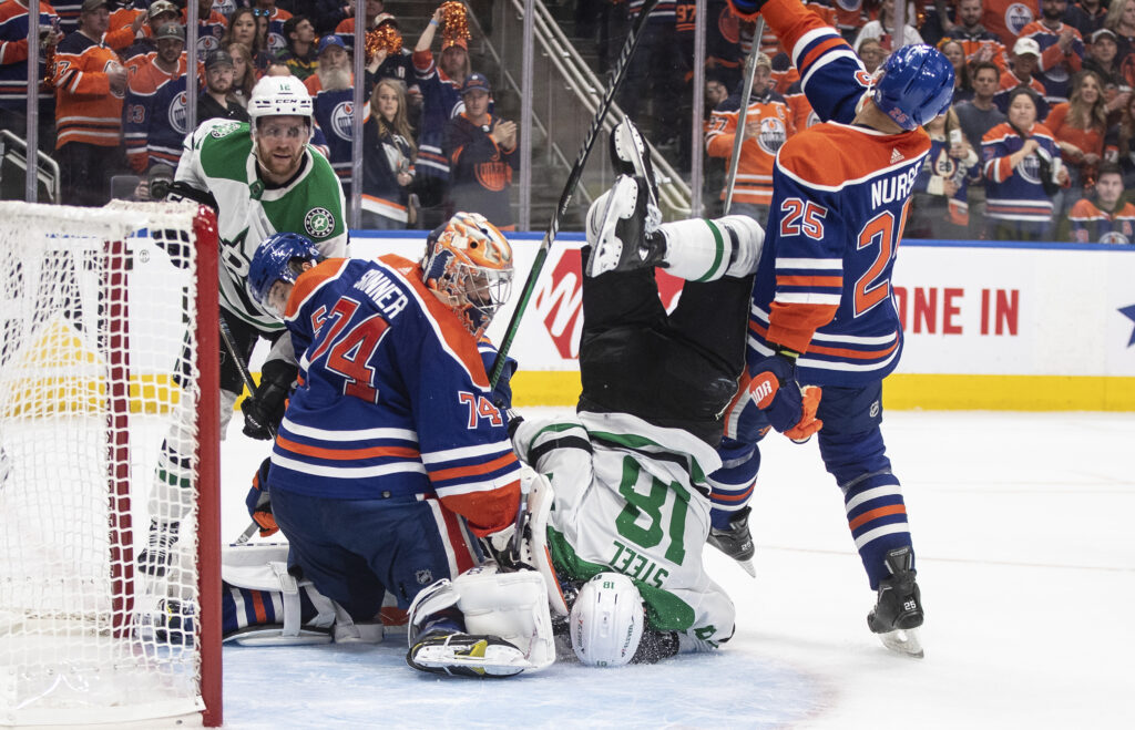 Dallas Stars' Sam Steel (18) is upended in front of the net as Edmonton Oilers goalie Stuart Skinner (74) makes a save during the third period of Game 4 of the Western Conference final in the NHL hockey Stanley Cup playoffs, Wednesday, May 29, 2024, in Edmonton, Alberta. (Jason Franson/The Canadian Press via AP)
