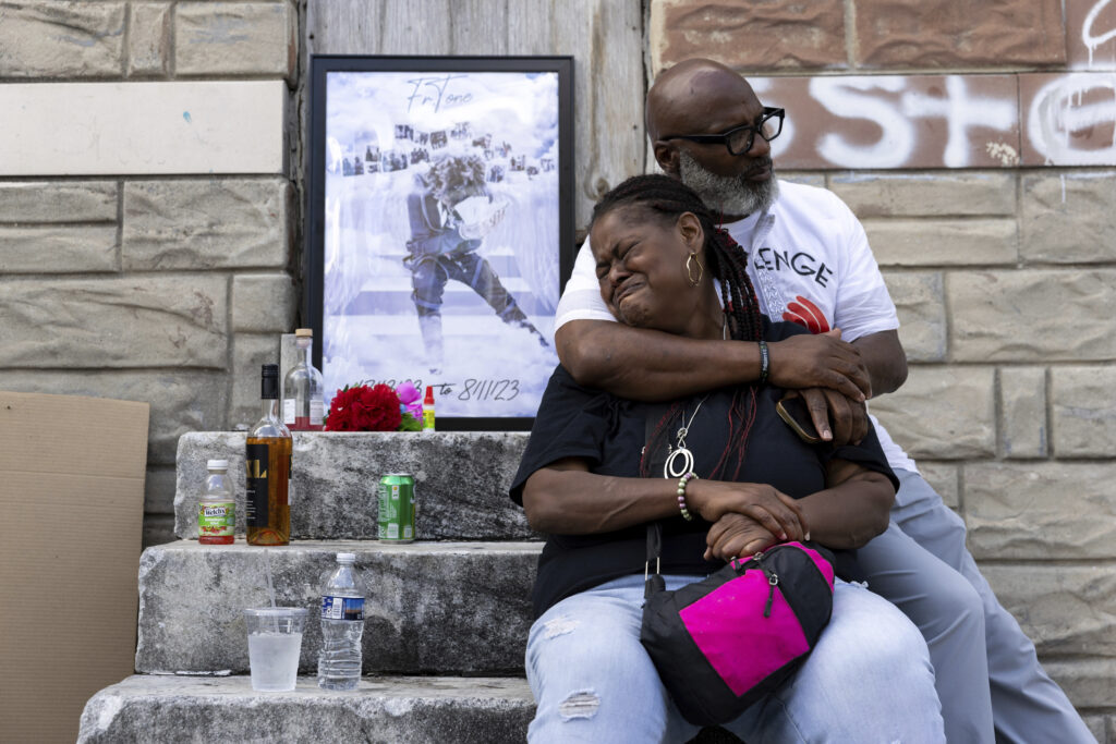 Antonio Lee's mother is comforted while mourning her son at a vigil, Friday, Aug. 18, 2023, in Baltimore. Lee, 19, was shot and killed while squeegeeing in Baltimore. Lee and childhood friend Antonio Moore grew up together in the streets of east Baltimore, surrounded by poverty and gun violence. But only one would make it out alive. Moore is a successful real estate investor and marketing consultant. Lee was shot and killed last summer, four months before his 20th birthday. (AP Photo/Julia Nikhinson)