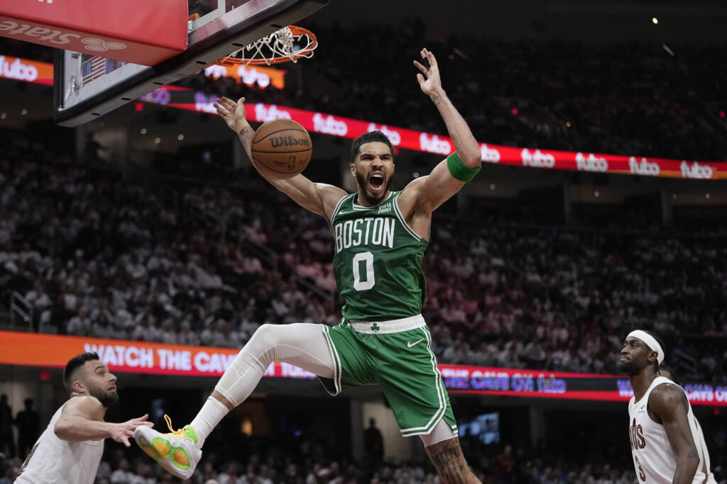 Boston Celtics forward Jayson Tatum dunks between Cleveland Cavaliers guard Max Strus, left, and guard Caris LeVert during the second half of Game 3 of an NBA basketball second-round playoff series Saturday, May 11, 2024, in Cleveland. (AP Photo/Sue Ogrocki)