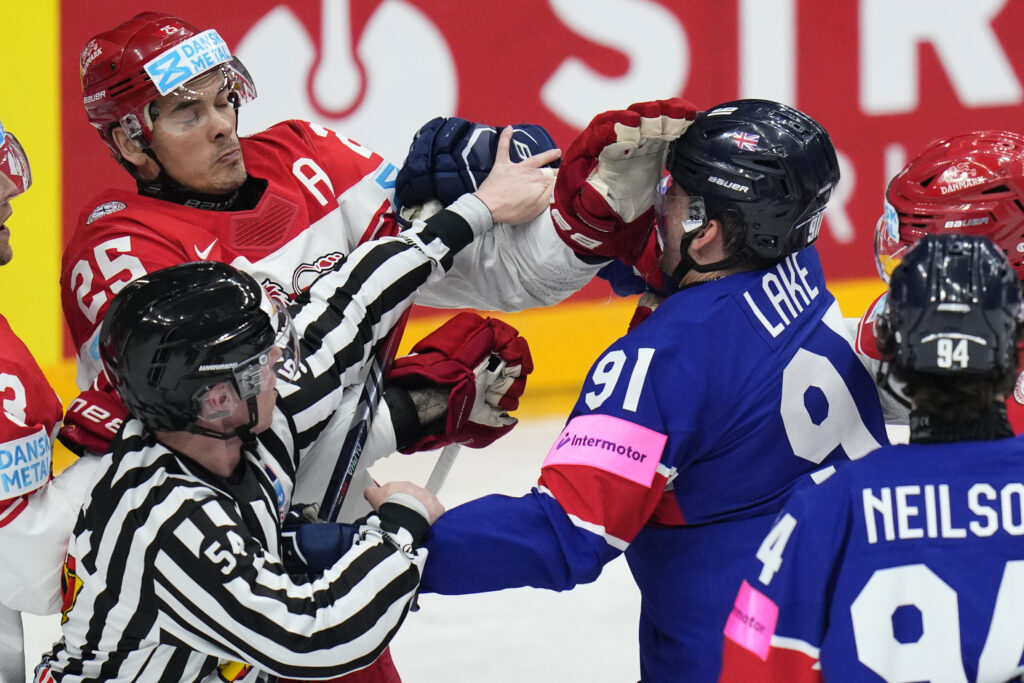 A referee tries to break up a fight between Denmark's Oliver Lauridsen, left, and Britain's Ben Lake during the preliminary round match between Great Britain and Denmark at the Ice Hockey World Championships in Prague, Czech Republic, Friday, May 17, 2024. (AP Photo/Petr David Josek)