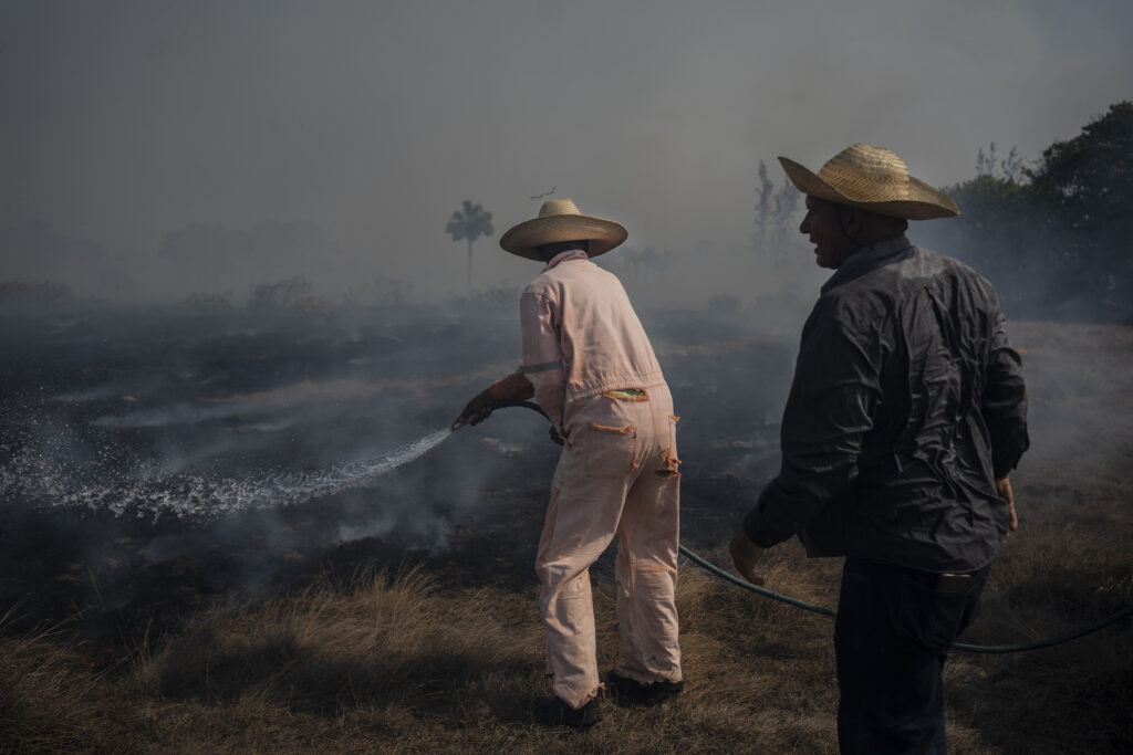 A resident works to extinguish flames from an approaching wildfire with a garden hose, in Rincón de la Palma, Veracruz state, Mexico, Saturday, May 18, 2024. (AP photo/Felix Marquez)
