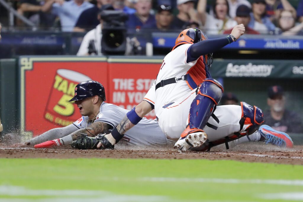 Cleveland Guardians' Brayan Rocchio, left, is safe on his slide into home plate on the RBI triple by Steven Kwan as Houston Astros catcher Victor Caratini, right, attempts the tag during the fifth inning of a baseball game Wednesday, May 1, 2024, in Houston. (AP Photo/Michael Wyke)
