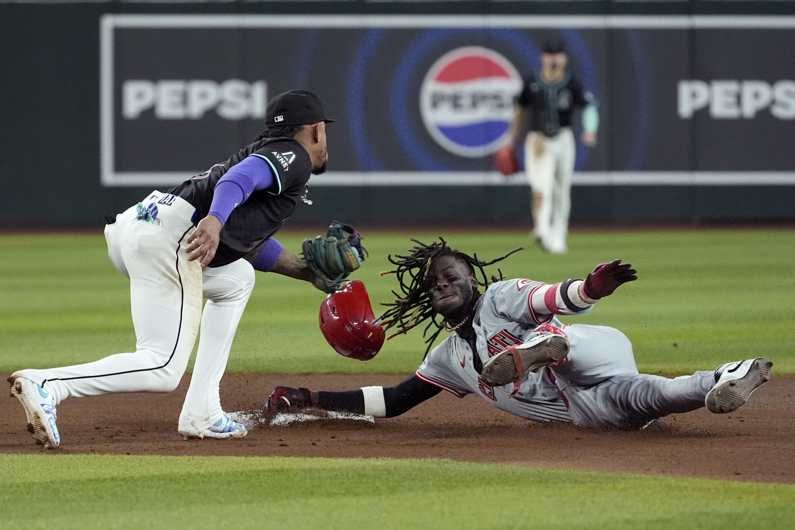 Arizona Diamondbacks second base Ketel Marte, left, tags out Cincinnati Reds shortstop Elly De La Cruz, right, at second base as De La Cruz tries to stretch a single into a double during the seventh inning of a baseball game Monday, May 13, 2024, in Phoenix. (AP Photo/Ross D. Franklin)