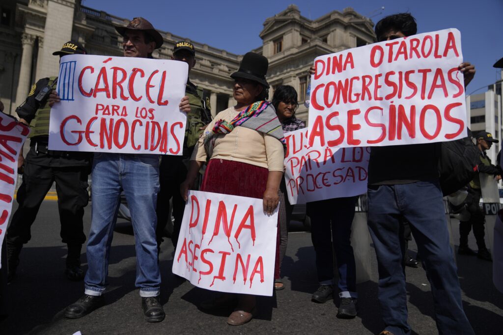 Anti-government protesters hold up signs critical of President Dina Boluarte and legislators, during a demonstration marking International Workers' Day, in Lima, Peru, Wednesday, May 1, 2024. (AP Photo/Martin Mejia)