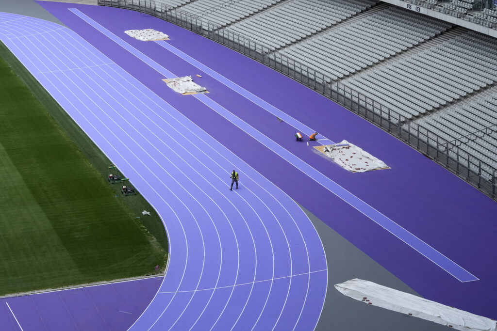 A worker crosses the track as preparations continue at the Stade de France ahead of the Paris Olympics, Tuesday, May 7, 2024, in Paris. The Paris Olympic games are set to begin in late July. (AP Photo/David J. Phillip)