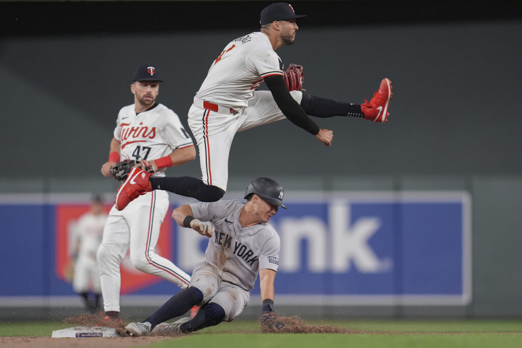 Minnesota Twins shortstop Carlos Correa jumps after outing New York Yankees' Anthony Volpe, bottom, to make a double play off a groundout hit by Juan Soto during the ninth inning of a baseball game Wednesday, May 15, 2024, in Minneapolis. (AP Photo/Abbie Parr)
