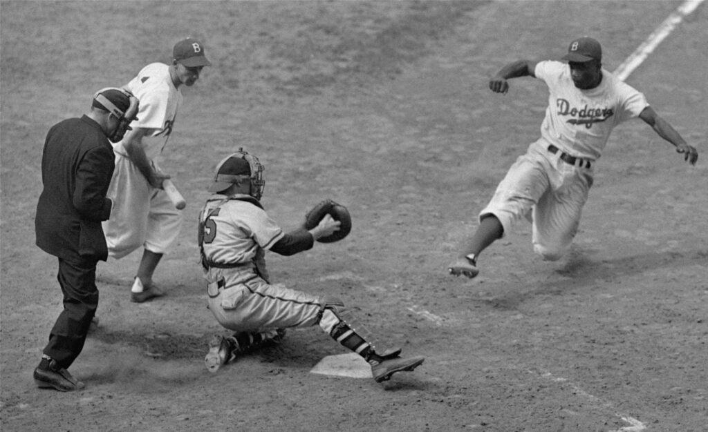 Jackie Robinson steals home in this game against the Boston Braves at Ebbets Field in August 1948.
