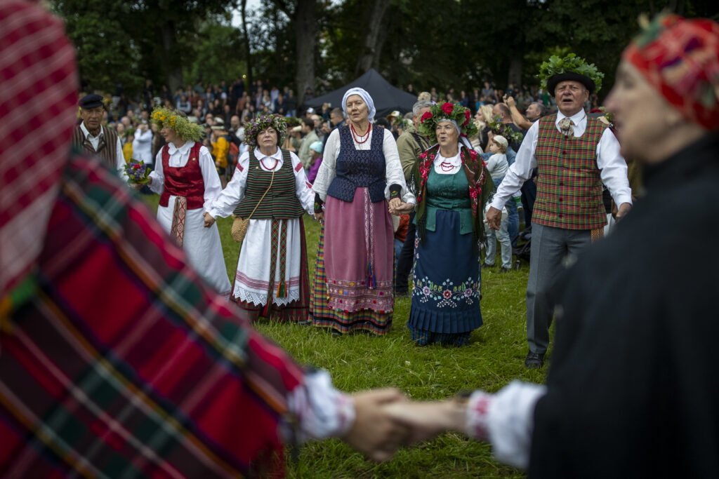People wearing traditional Lithuanian village-style clothes dance as they celebrate Saint John's Day and the summer solstice in the small town of Kernave, some 35km (22 miles) northwest of the capital, Vilnius, Lithuania, on Sunday, June 23, 2024. St. John's Day, or Midsummer Day, the shortest night of the year, is celebrated with festivities that include making oak leaf wreaths, leaping over flames, and encouraging young people to go out and look for fern flowers. (AP Photo/Mindaugas Kulbis)