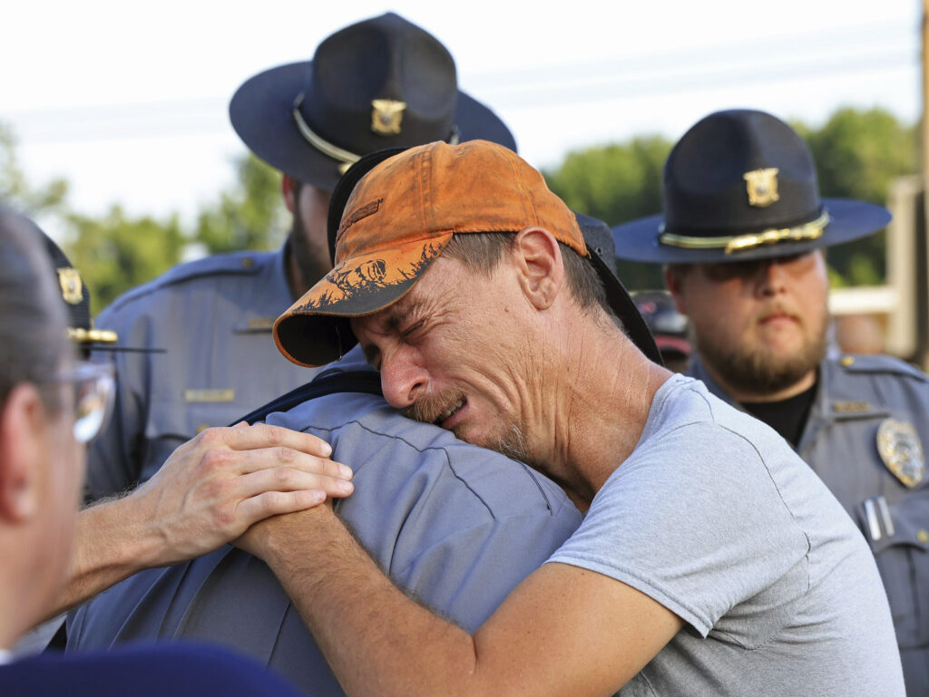 Bo Lanthrop, right, embraces a member of the Fordyce Police Department during a candlelight vigil in the parking lot of the Mad Butcher grocery store in honor of the victims of Friday's mass shooting, in Fordyce, Ark., Sunday, June 23, 2024. (Colin Murphey/Arkansas Democrat-Gazette via AP)