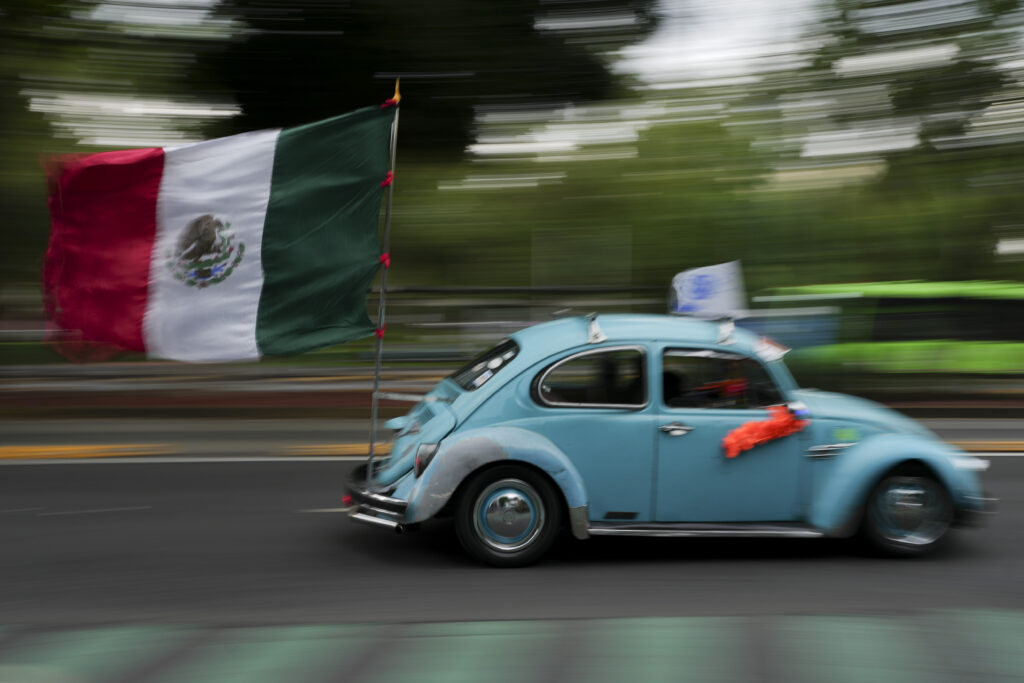 An antique Volkswagen Beetle, known in Mexico as a "vocho," parades through the streets a day after World Vocho Day, in Mexico City, Sunday, June 23, 2024. (AP Photo/Marco Ugarte)