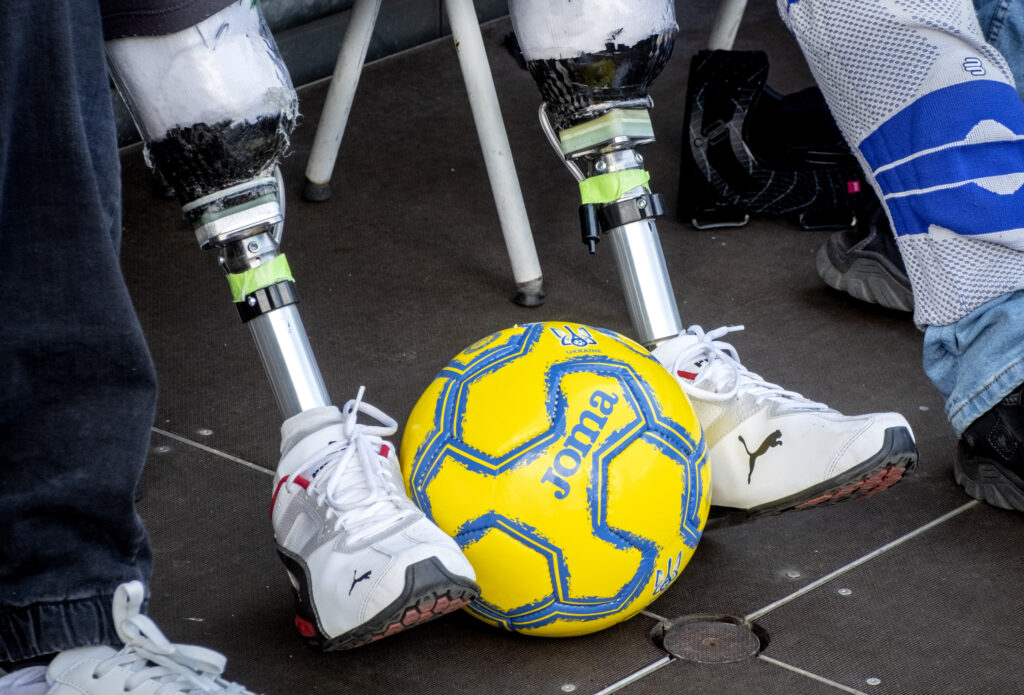 A Ukrainian war veteran with leg prosthesis watches players of Ukraine's national soccer team during a public training session in Wiesbaden, Germany, Thursday, June 13, 2024, ahead of their group E match against Romania at the Euro 2024 soccer tournament. (AP Photo/Michael Probst)