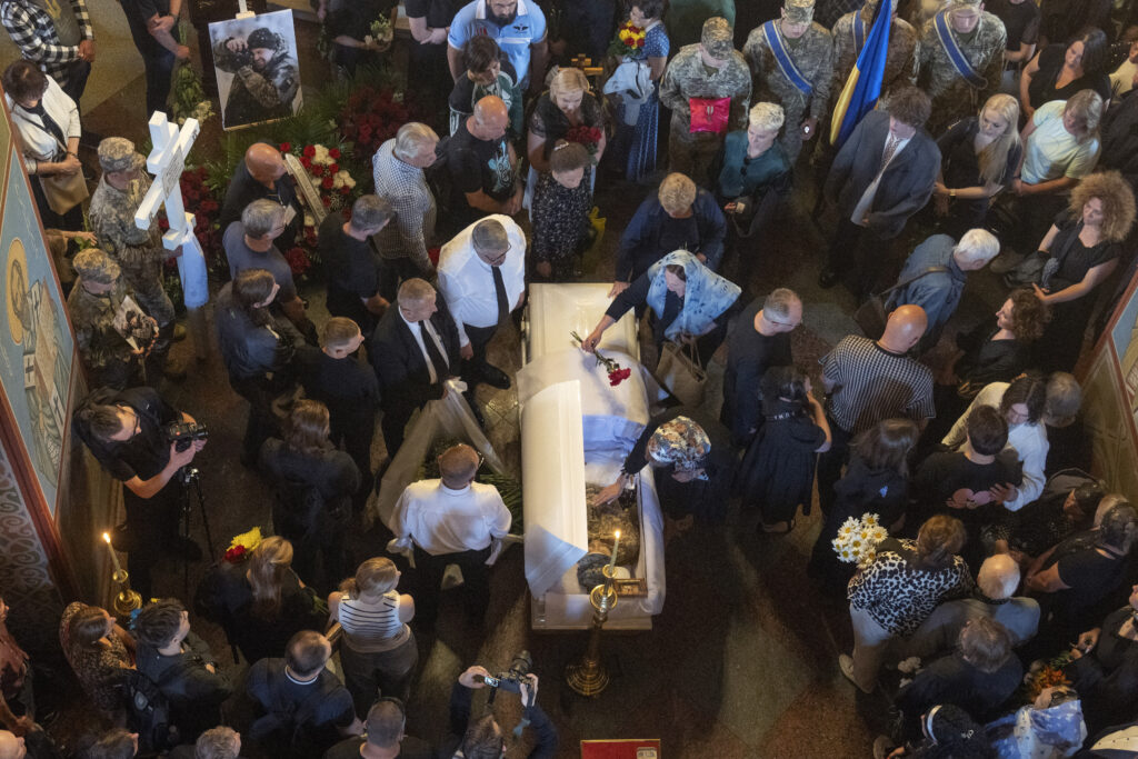 People pay their last respects at the coffin of Ukrainian serviceman, photographer Arsen Fedosenko, who was killed in a battle with the Russian troops, during the funeral ceremony in St. Michael Cathedral in Kyiv, Ukraine, Thursday, June 13, 2024. (AP Photo/Efrem Lukatsky)