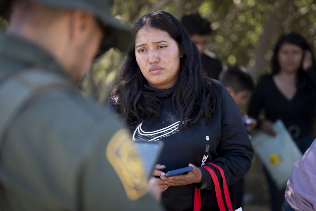 A migrant woman from Mexico talks with a Border Patrol agent before being transported in a van to be processed for asylum, Wednesday, June 5, 2024, near Dulzura, Calif. President Joe Biden on Tuesday unveiled plans to enact immediate significant restrictions on migrants seeking asylum at the U.S.-Mexico border as the White House tries to neutralize immigration as a political liability ahead of the November elections. (AP Photo/Gregory Bull)