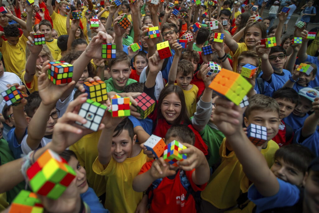 Students take part in a flash mob held on the occasion of the 50th anniversary of the invention of the Rubik's Cube organized by the National Innovation Agency at Szent Istvan Square in downtown Budapest, Hungary, Wednesday, June 12, 2024. Hungarian professor, architect and inventor Erno Rubik invented the so-called Magic Cube 50 years ago, in the spring of 1974, which originally served for educational purposes. The game later became popular as Rubik's Cube worldwide. (Zoltan Balogh/MTI via AP)