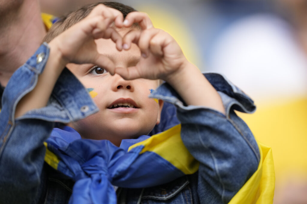 A Ukrainian child makes a heart sign ahead of a Group E match between Slovakia and Ukraine at the Euro 2024 soccer tournament in Duesseldorf, Germany, Friday, June 21, 2024. (AP Photo/Andreea Alexandru)