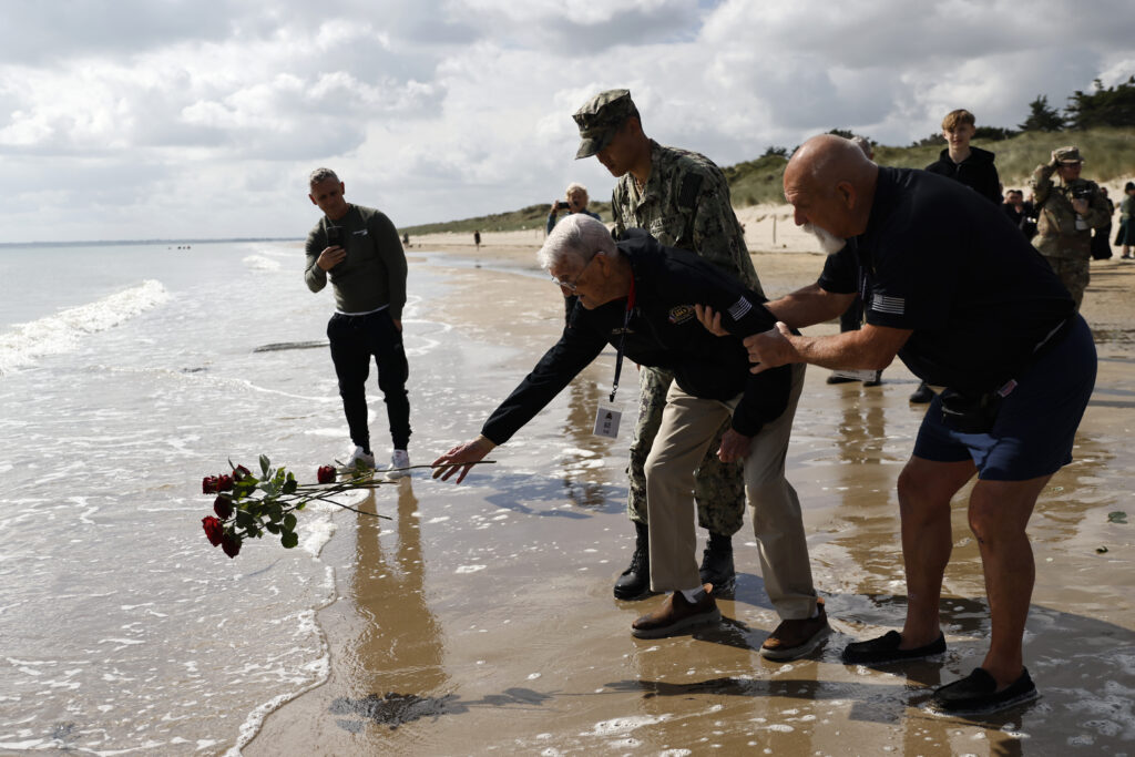 American WWII veteran Bill Wall throws roses into the water during a wreath-laying ceremony at Utah Beach, Wednesday, June 5, 2024 at Utah Beach, Normandy,. World War II veterans from across the United States as well as Britain and Canada are in Normandy this week to mark 80 years since the D-Day landings that helped lead to Hitler's defeat. (AP Photo/Jeremias Gonzalez)