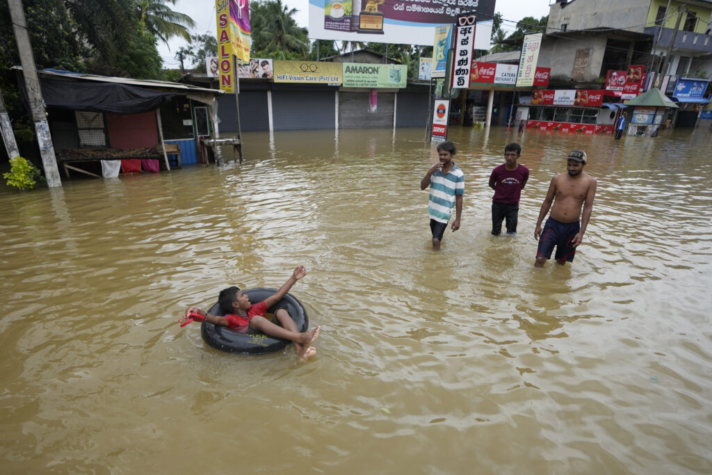 A boy plays with an inflatable rubber tube in a flooded street in Biyagama, a suburb of Colombo, Sri Lanka, Monday, Jun. 3, 2023. Sri Lanka closed schools on Monday as heavy rains triggered floods and mudslides in many parts of the island nation, killing at least 10 people while six others have gone missing, officials said. (AP Photo/Eranga Jayawardena)