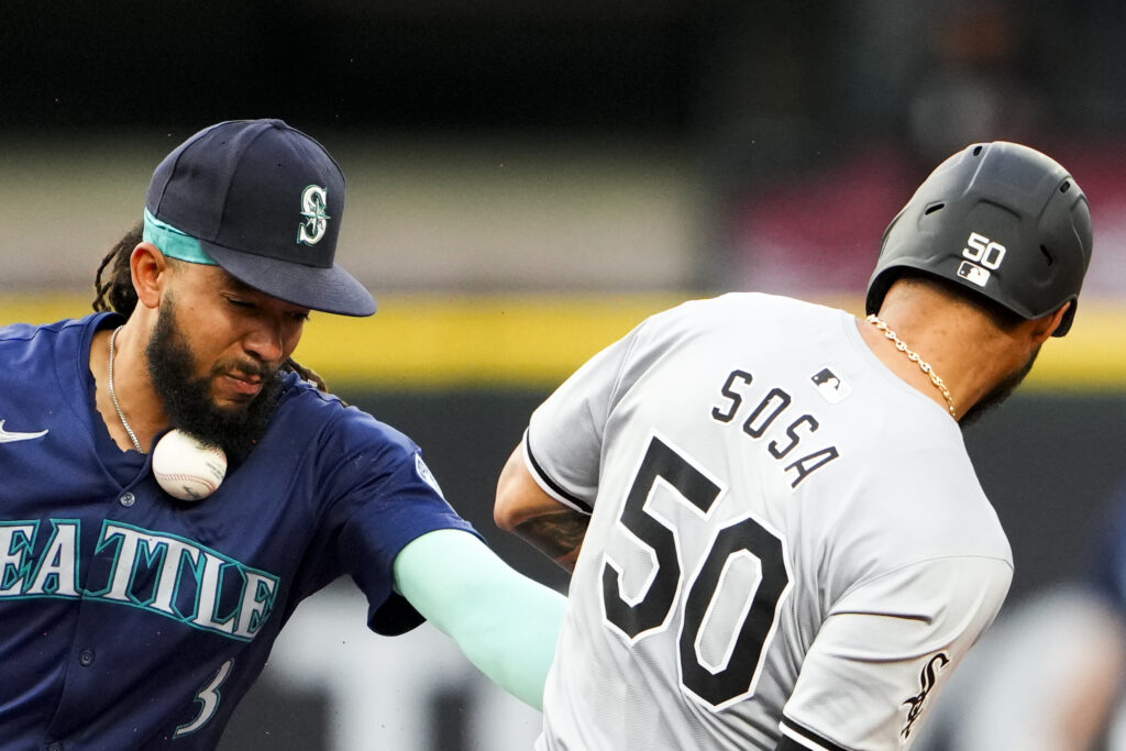 Seattle Mariners shortstop J.P. Crawford, left, can't make the tag on Chicago White Sox's Lenyn Sosa as the ball hits him in the neck during the seventh inning of a baseball game Monday, June 10, 2024, in Seattle. (AP Photo/Lindsey Wasson)