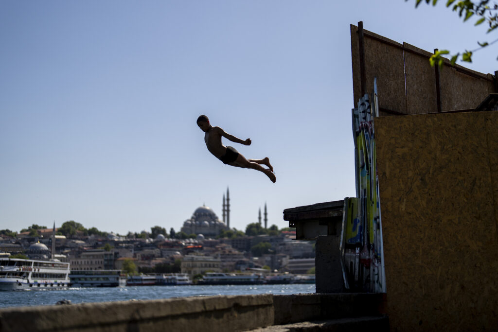 A youngster dives into the Bosphorus to cool off during a summer day in Istanbul, Turkey, Thursday, June 27, 2024. (AP Photo/Francisco Seco)