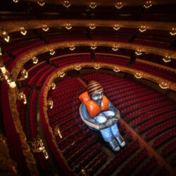 Sitting alone in a sea of empty red velvet chairs, a 6-meter-tall giant 'Inflatable Refugee' is photographed at Barcelona's Gran Teatre de Liceu opera house, Spain, Wednesday, June 12, 2024. Created by Belgian visual artists Schellekens & Peleman in 2015 following the refugee crisis in Europe by, they hope it to spark debate around the plight of refugees. The artistic intervention coincided with an alarming record: 120 million people around the world have been forcibly displaced from their homes due to conflict and other protracted crises, the U.N. Refugee announced on Thursday. (AP Photo/Emilio Morenatti)