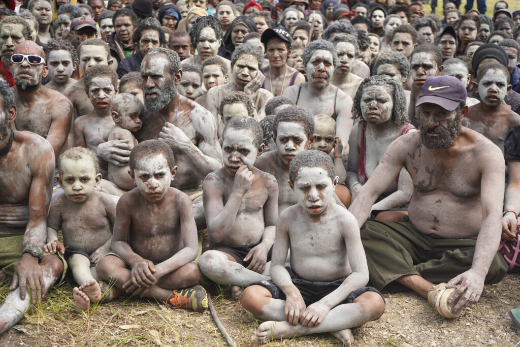 A group of survivors from the May 24 landslide in Inga Province, are smeared in mud as a sign of mourning, gather at an event where Prime Minister James Marape was to address them at Kaokalom village, in the highlands of Papua New Guinea, Friday May 31, 2024. Marape visited the site of a major landslide, which is estimated to have buried hundreds of villagers in the South Pacific island nation's mountainous interior over a week ago and left the ground too unstable for heavy earthmoving machines to help clear up the mess. (Noreen Chambers, UNICEF PNG via AP)