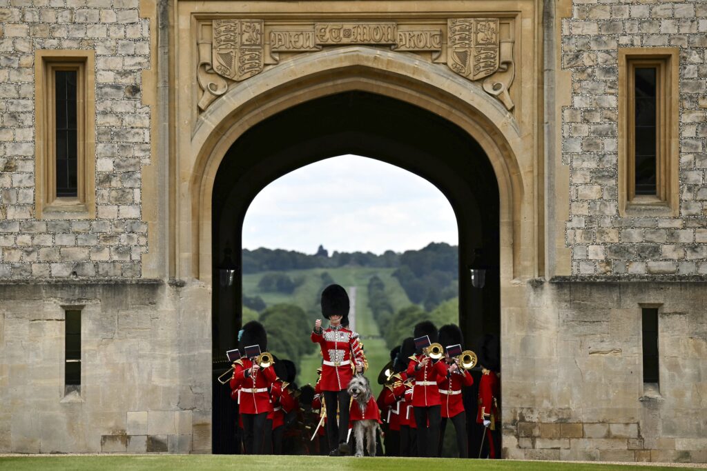 The Band of the Irish Guards, led by the Irish Guards' Regimental Mascot, an Irish wolfhound named Seamus (Turlough Mor), march into Windsor Castle's Quadrangle through the George IV Gate during a ceremony where Britain's King Charles III will present New Colours to No 9 and No 12 Company of the Irish Guards, at Windsor Castle, Windsor, England, Monday, June 10, 2024. The new Colours will be those trooped in the Trooping of the Colour at His Majesty's official Birthday Parade in London on Saturday June 15, 2024. (Ben Stansall/Pool Photo via AP)