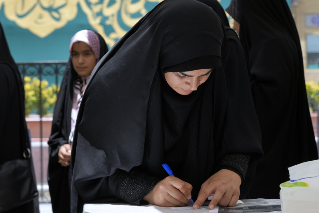 A woman fills out her ballot during the Iranian presidential election in a polling station at the shrine of Saint Saleh in northern Tehran, Iran, Friday, June 28, 2024. Iranians were voting Friday in a snap election to replace the late President Ebrahim Raisi, killed in a helicopter crash last month, as public apathy has become pervasive in the Islamic Republic after years of economic woes, mass protests and tensions in the Middle East. (AP Photo/Vahid Salemi)