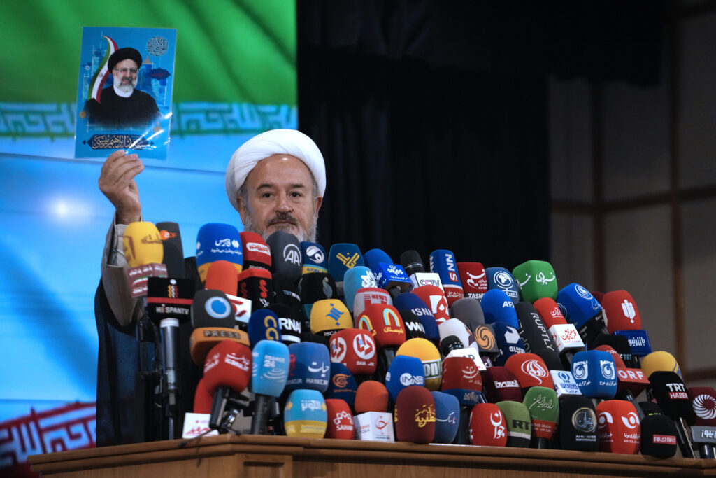 Iranian cleric Ahmad Akbari shows a portrait of the late President Ebrahim Raisi, who was killed in a helicopter crash in May, at the conclusion of a press briefing after registering his name as candidate for the June 28 presidential election at the Interior Ministry, in Tehran, Iran, Monday, June 3, 2024. All candidates must be approved by Iran's 12-member Guardian Council, a panel of clerics and jurists ultimately overseen by the Supreme Leader Ayatollah Ali Khamenei. (AP Photo/Vahid Salemi)