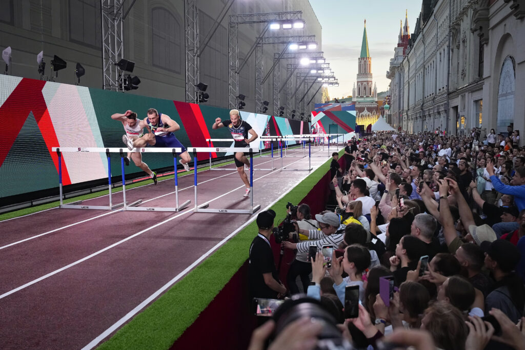 Athletes compete in the men's 60-meter hurdles during the first day of the Week of track and field in Nikolskaya street near the Kremlin, background, and Red Square in Moscow, Tuesday, June 4, 2024. (AP Photo/Alexander Zemlianichenko)