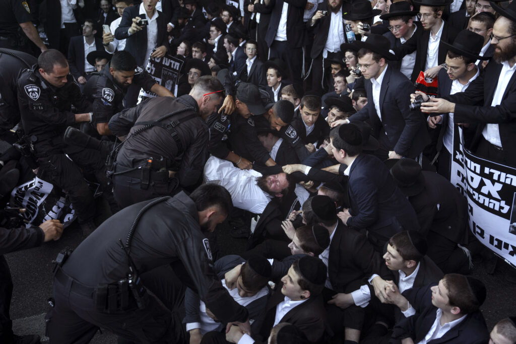 Israeli police officers disperse Ultra-Orthodox Jews blocking a highway during a protest against army recruitment in Bnei Brak, Israel, Thursday, June 27, 2024. Israel's Supreme Court unanimously ordered the government to begin drafting ultra-Orthodox Jewish men into the army — a landmark ruling seeking to end a system that has allowed them to avoid enlistment into compulsory military service. (AP Photo/Oded Balilty)