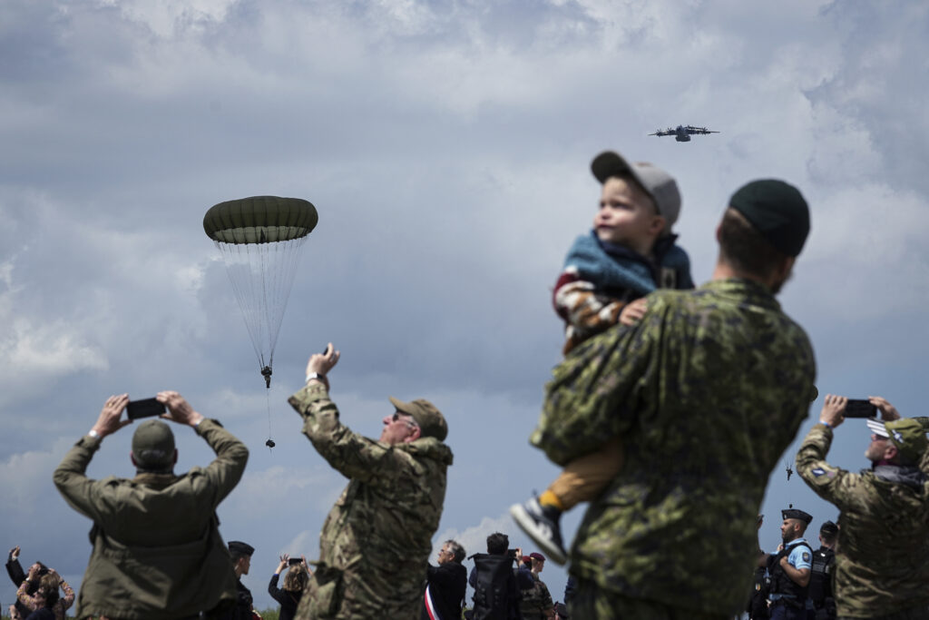 People attend a multinational parachute drop as some 400 British, Belgian, Canadian and US paratroopers jump to commemorate the contribution of airborne forces on D-Day. as part of the 80th anniversary of D-Day, in Sannerville, Normandy, France, Wednesday, June 5, 2024. Veterans and world dignitaries gather in Normandy to commemorate the 80th anniversary of the landings. (AP Photo/Laurent Cipriani)