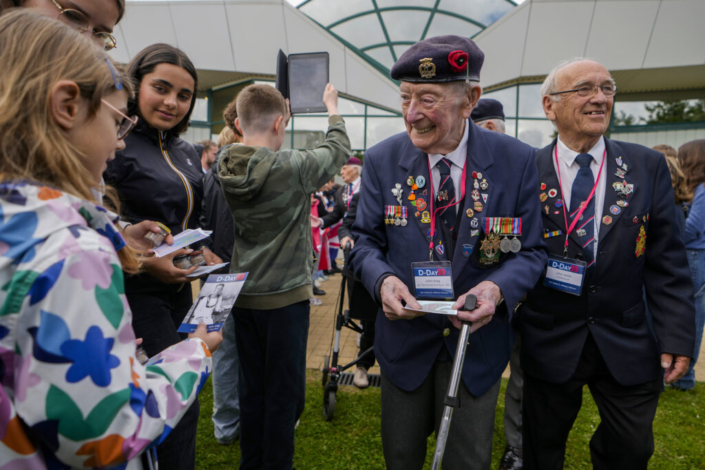 British World War II veteran John King is greeted by a young girl prior to a service at the Pegasus Bridge memorial in Benouville, France, Normandy, Wednesday, June 5, 2024. World War II veterans from across the United States as well as Britain and Canada are in Normandy this week to mark 80 years since the D-Day landings that helped lead to Hitler's defeat. (AP Photo/Virginia Mayo)