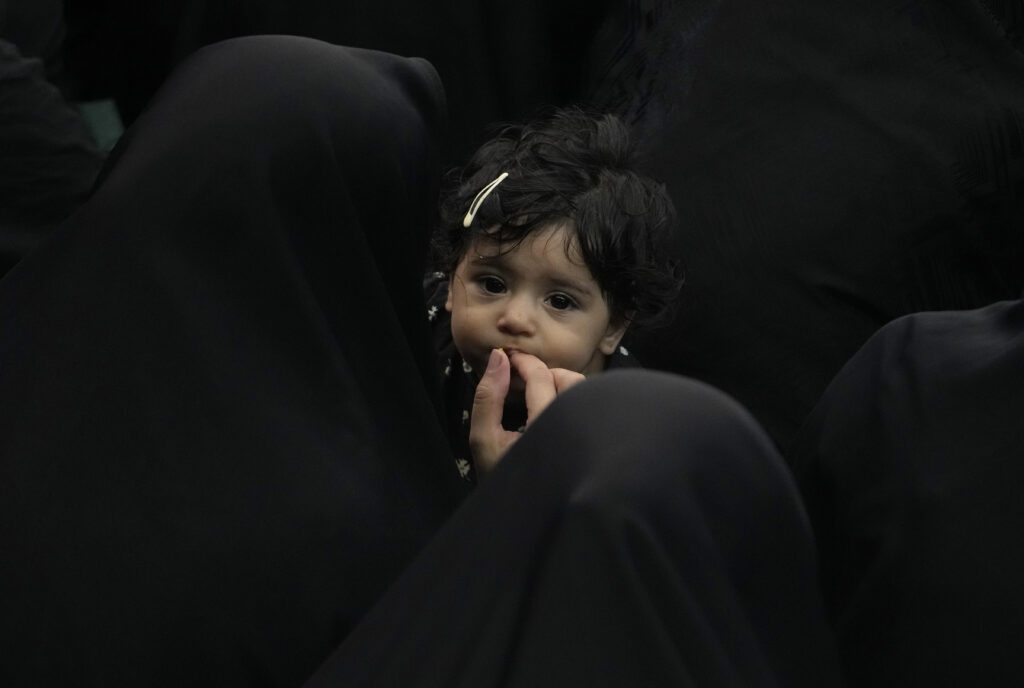 An Iranian Shiite Muslim woman feeds her child as they participate in the Ashura mourning ritual, which commemorates the 7th century martyrdom of Hussein, the grandson of the Prophet Muhammad, in the Battle of Karbala in modern-day Iraq, at the old main bazaar of Tehran, Iran, Tuesday, July 16, 2024. Shiites make up over 10% of the world's 1.8 billion Muslims and consider Hussein the rightful successor of the Prophet Muhammad. (AP Photo/Vahid Salemi)
