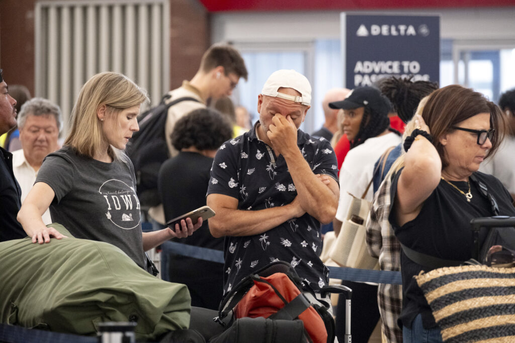 Tiffany McAllister and Andres Bernal try to rebook their flight to Iowa while at Hartsfield Jackson International Airport in Atlanta, Friday, July 19, 2024, as a major internet outage disrupts flights, banks, media outlets and companies across the world. (AP Photo/Ben Gray)