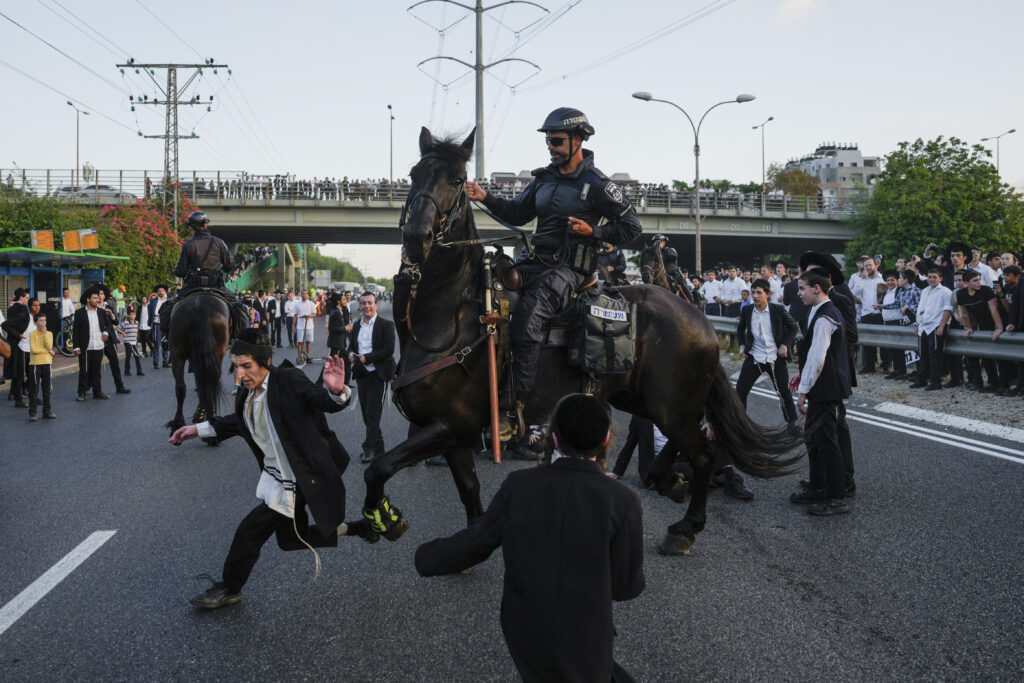 Israeli mounted police disperse ultra-Orthodox Jews blocking a highway during a protest against soldier recruitment in Bnei Brak, near Tel Aviv, Israel, Tuesday, July 16, 2024. The Israeli military said Tuesday it will begin mailing draft notices to Jewish ultra-Orthodox men next week, a move that could destabilize Prime Minister Benjamin Netanyahu's government and spark more large protests in the community. (AP Photo/Ohad Zwigenberg)