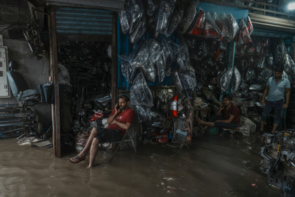 Auto repair shop employees watch water level rise inside their shop during monsoon rains in Mumbai, India, Thursday, July 25, 2024. (AP Photo/Rafiq Maqbool)